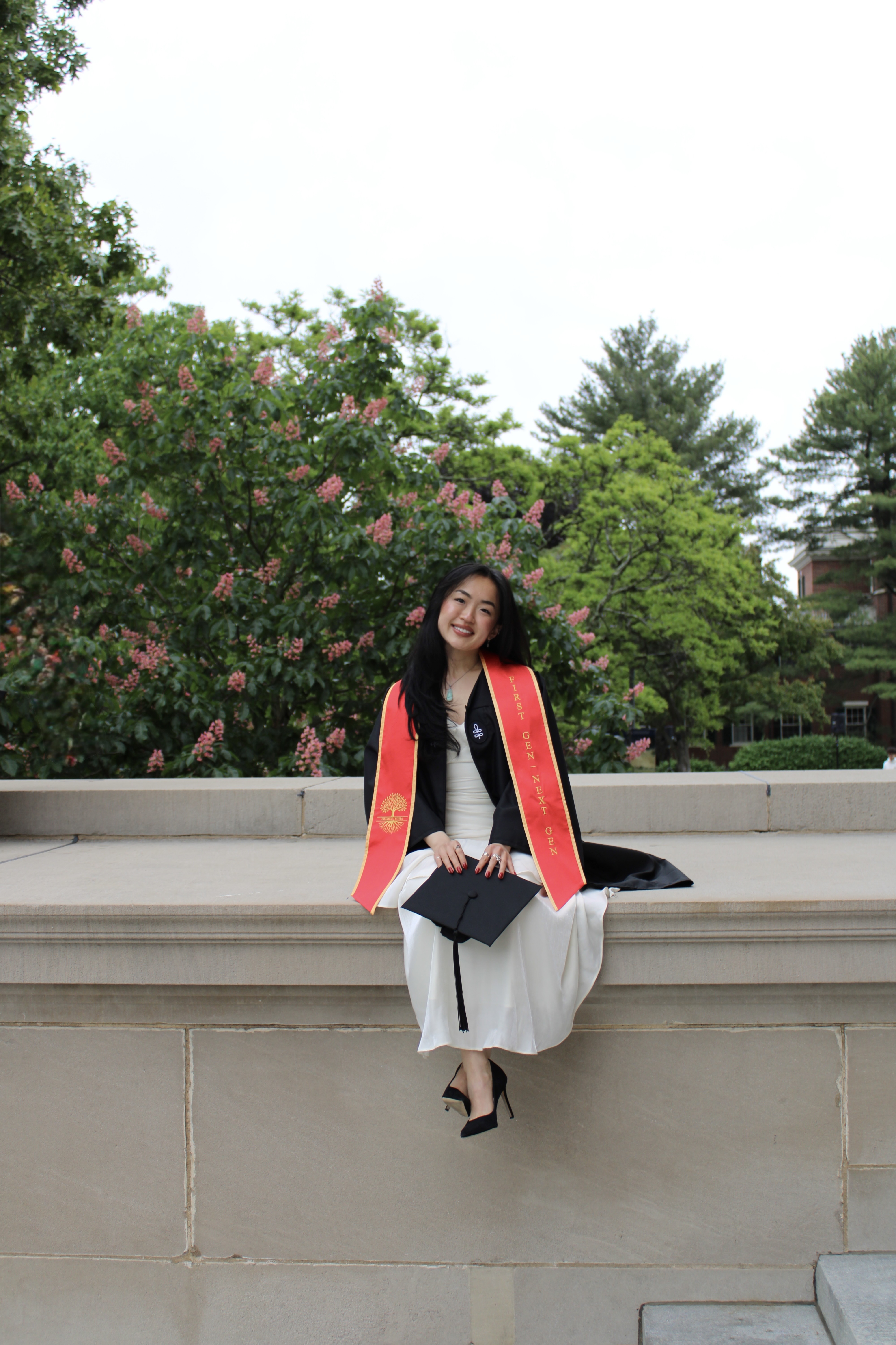 Sunny Shi sitting in her Harvard graduation regalia.