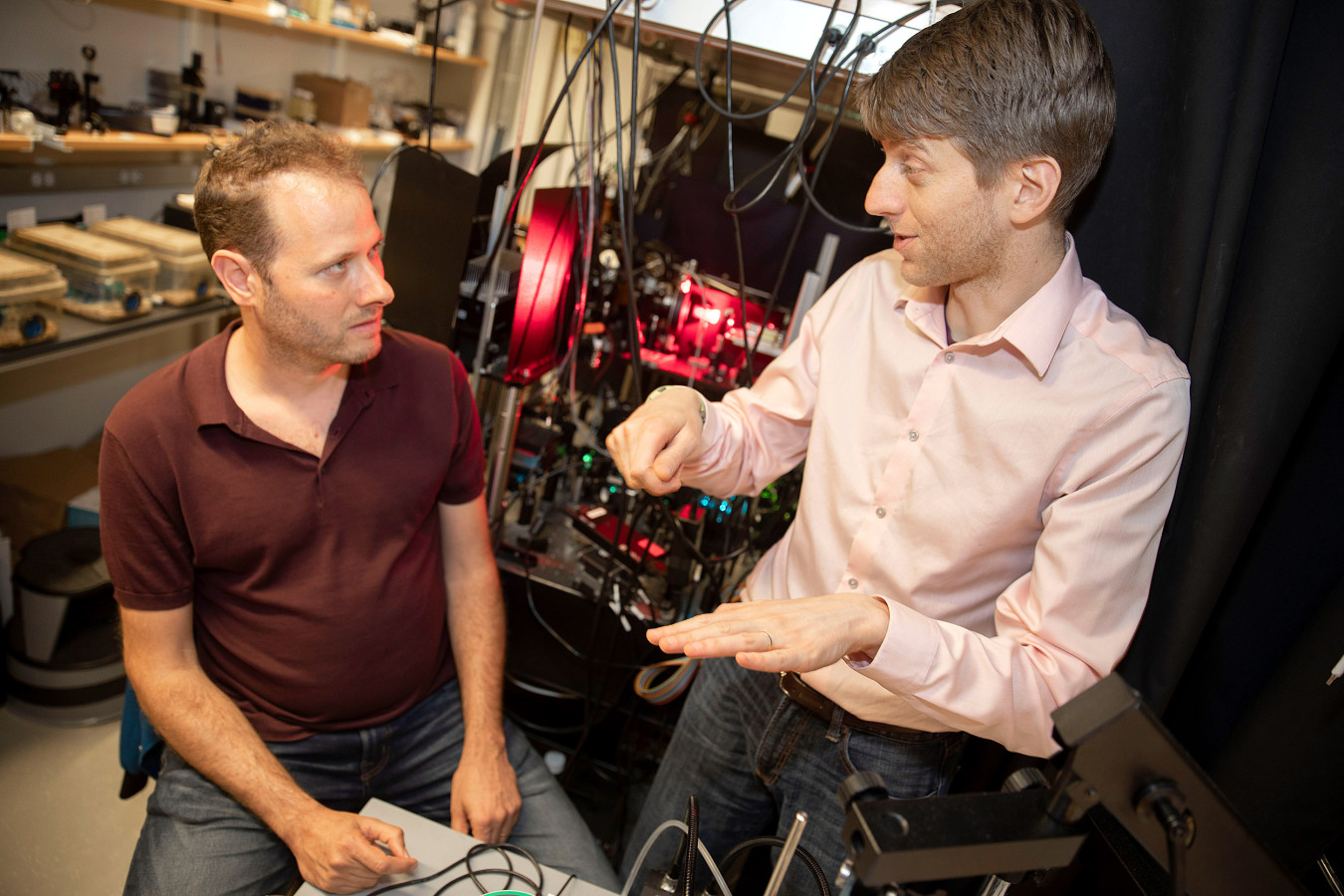 Adam Cohen (right) and Yoav Adam (left) discuss their findings in front of their homemade technology, which glows red