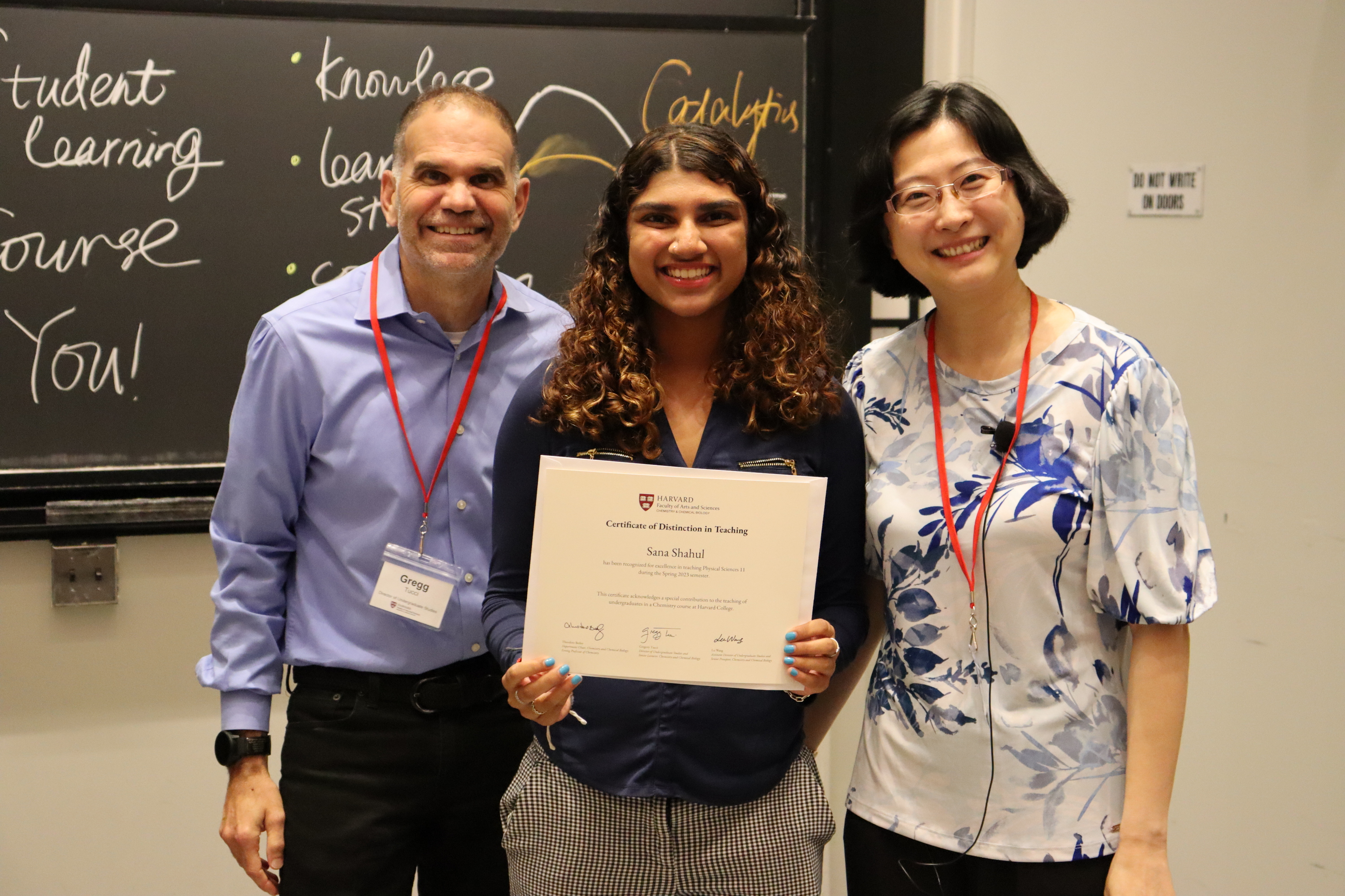 Two CCB faculty members stand with a student between them, holding an award
