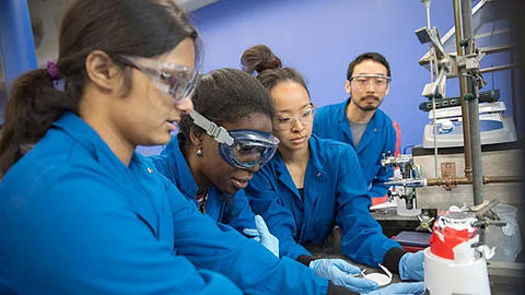 A lab Teaching Fellow works with 3 lab students at a bunch