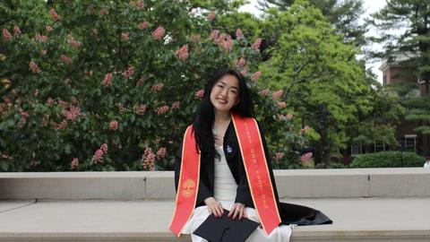 Sunny Shi sitting in her Harvard graduation regalia.