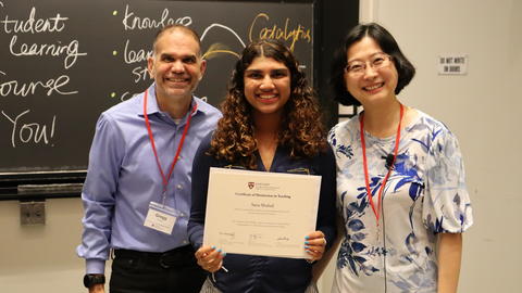 Two CCB faculty members stand with a student between them, holding an award