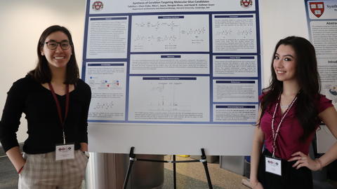 Two undergraduates stand in front of a research poster
