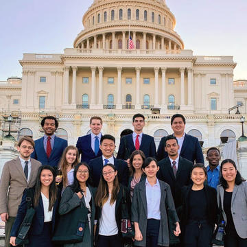 Chemistry students dressed in suits pose for a photo on the steps of the Capitol building in the soft light of morning
