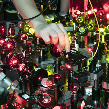 A hand reaches into a chaotic mess of lasers
