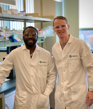 A photo of Niyi Fadeyi and Rob Oslund wearing lab coats in a lab