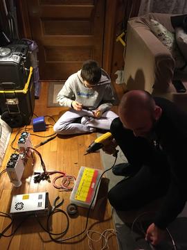 A photo of Metalmark co-founders Tanya and Elijah Shirman in their living room with their children, who are helping them build their demo system