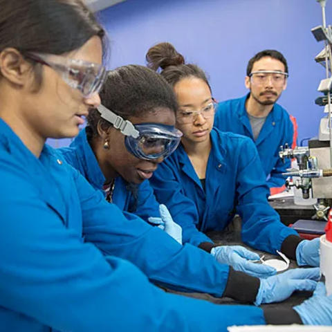 A lab Teaching Fellow works with 3 lab students at a bunch