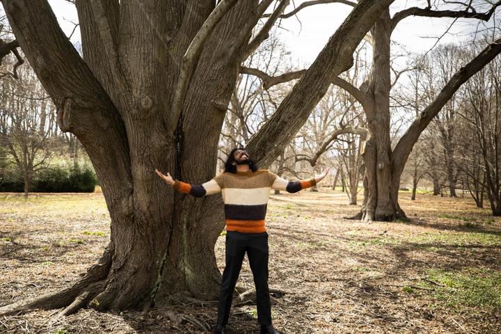 A photo of Suhaas Bhat standing under a big tree with his hands outstretched