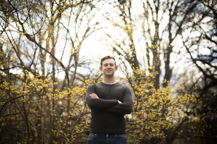 A photo of James Healy standing in front of trees with fresh yellow pollen