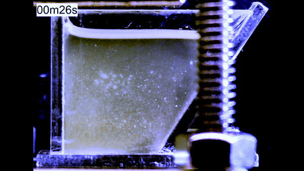 In a clear container, a murky substance swirls until three distinct white clouds of fentanyl, heroin, and lactose form