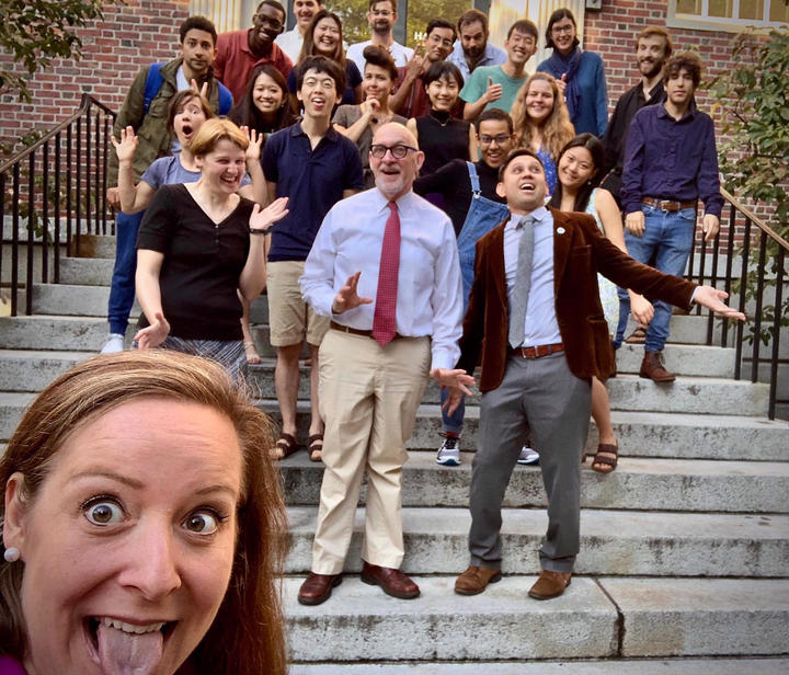 A photo of students and staff at the GSAS Student Center celebrating on the steps outside