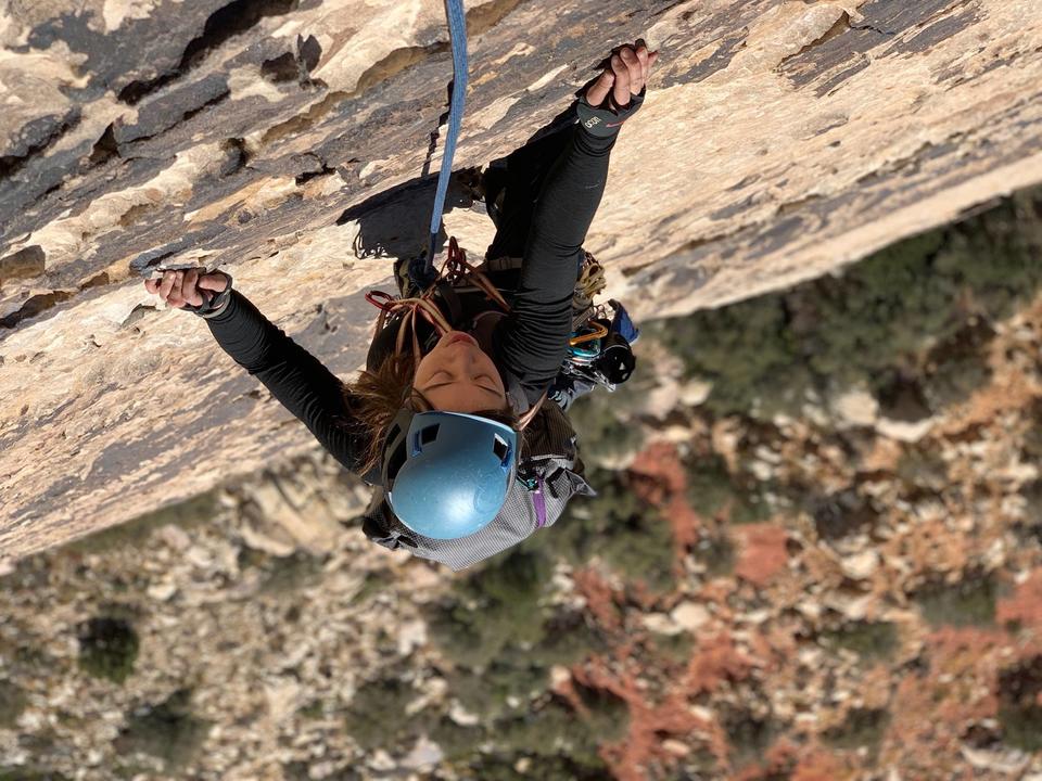 A photo taken from above of Christina rock climbing high up on a cliff