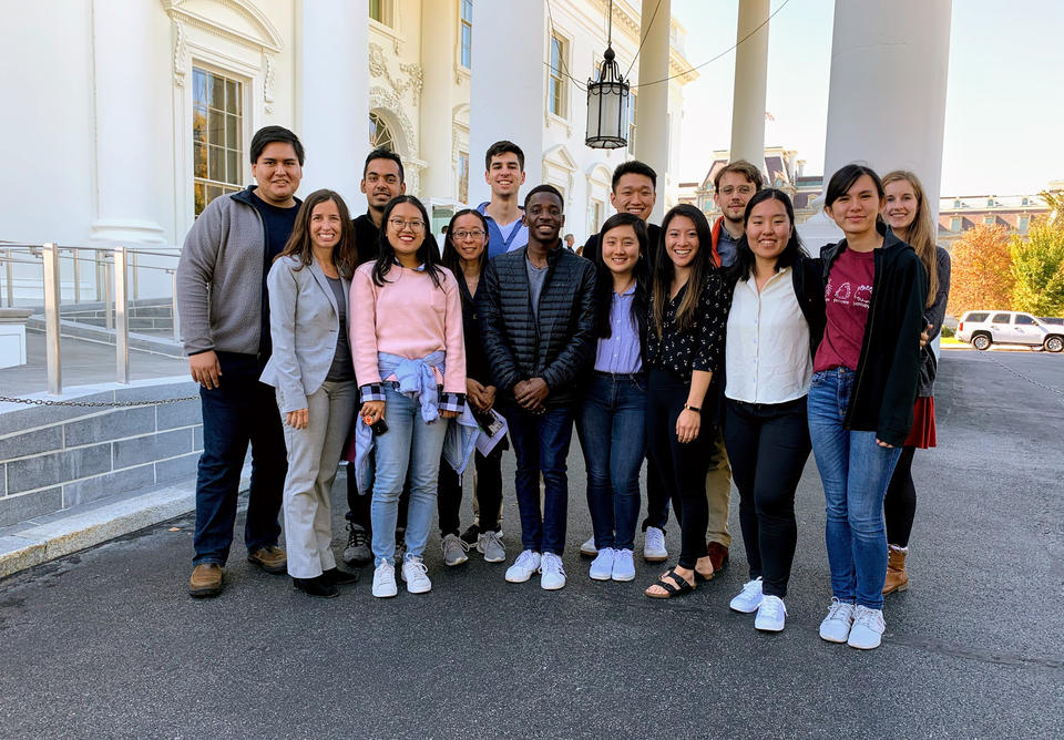 A photo of the students, teaching fellows, and Vollmer-Snarr standing underneath a White House awning