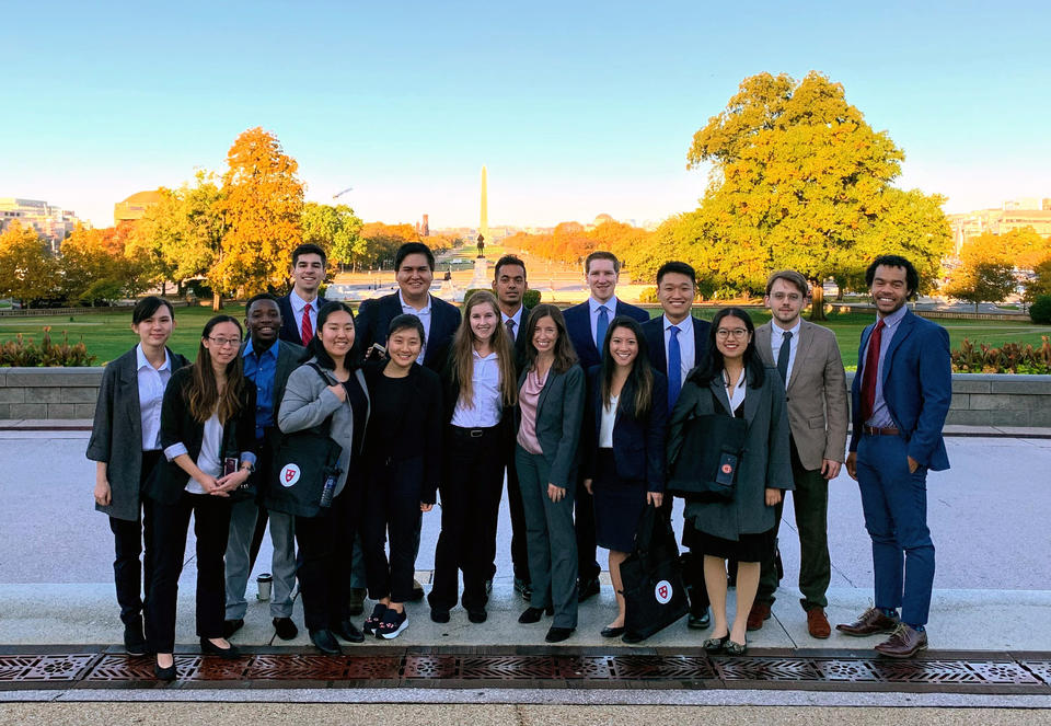Chemistry students and teachers pose in their suits for a photo on the National Mall, the Washington monument like a glowing needle in the background