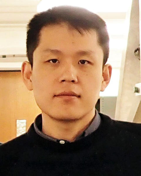 A headshot of Suyang Xu wearing a black sweater, looking directly at the camera